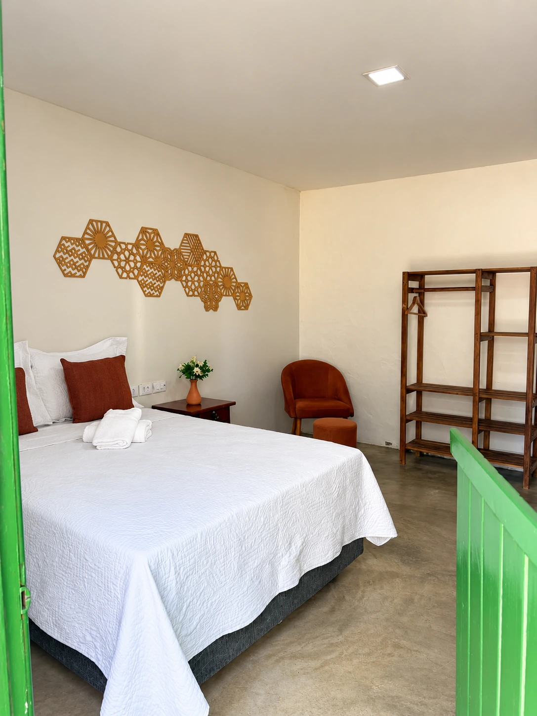 Acomodação com cama de casal, enxoval branco e porta verde